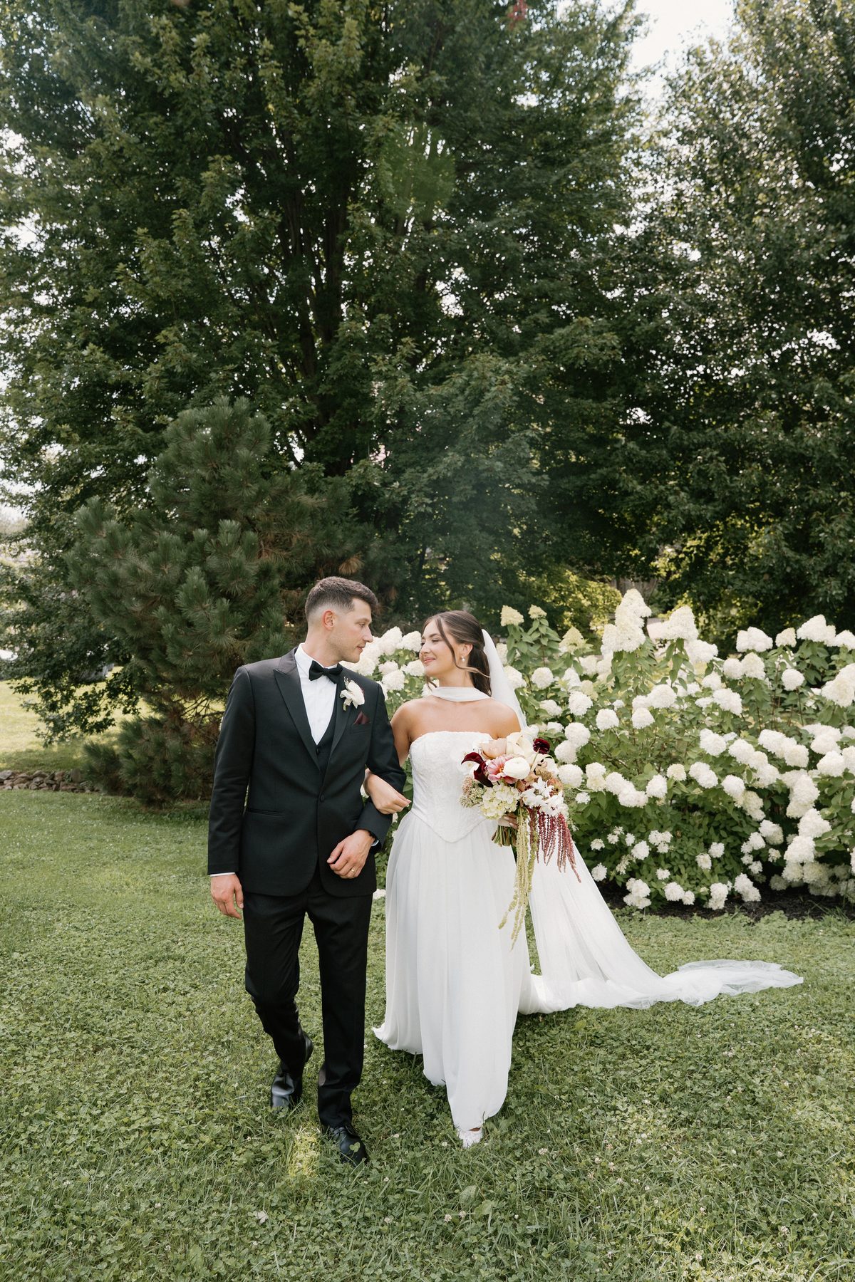 Bride and groom beside white hydrangeas — GISS Beauty bridal makeup