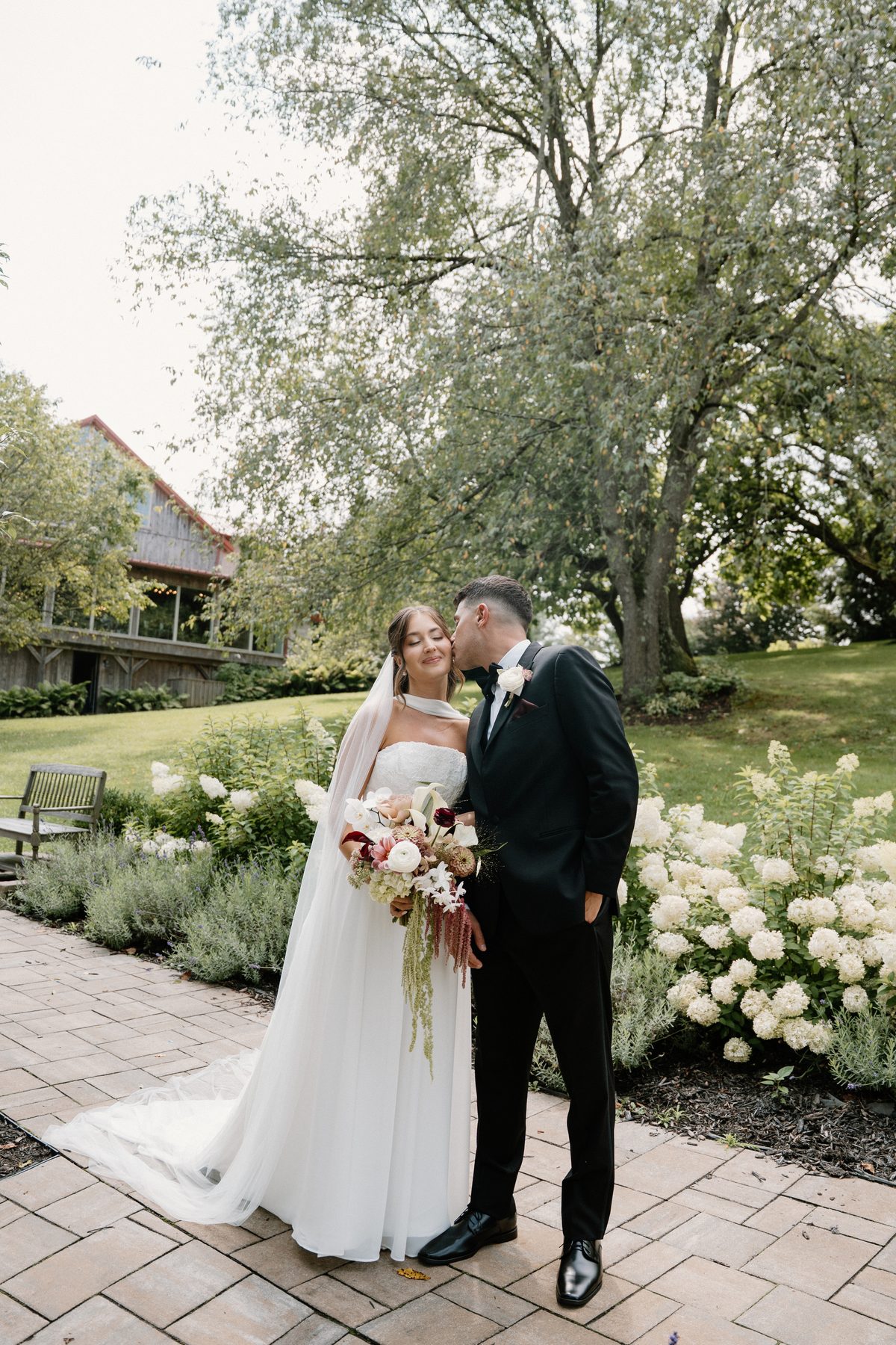 Bride and groom embracing in a garden — wedding makeup by GISS Beauty